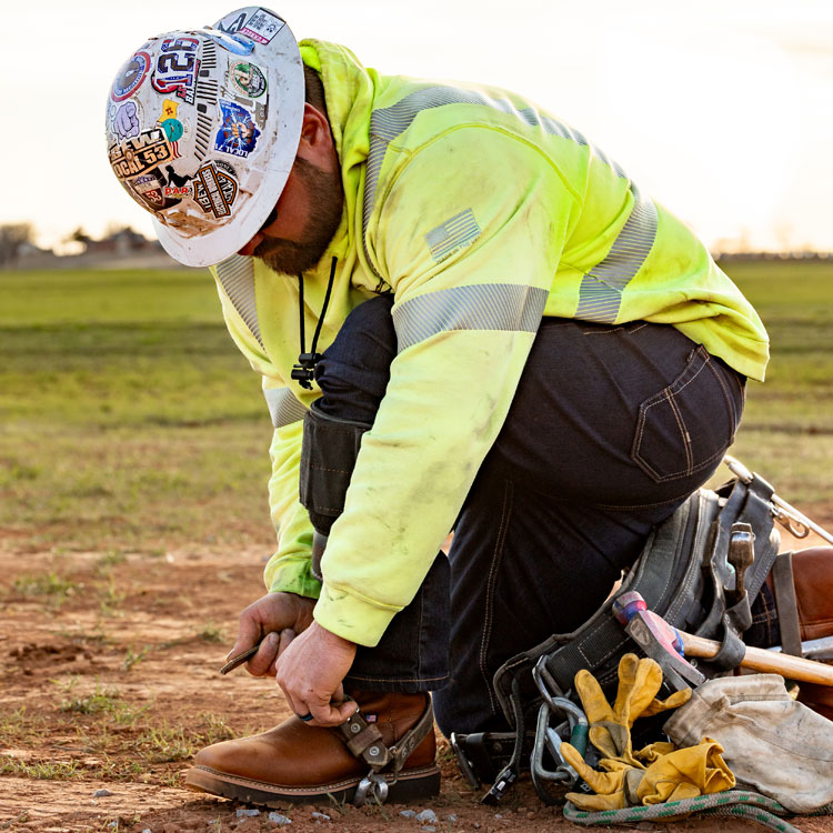 A man wearing Justin boots, a hard hat and a hi visibility jacket.